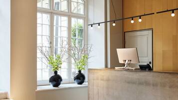 A reception area with a marble staircase, a reception desk, and a large window with plants.
