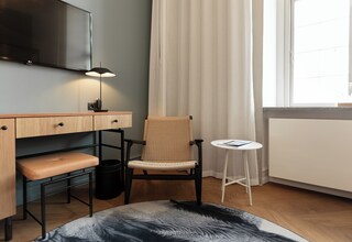 A modern room with a desk, chair, and a small table.
