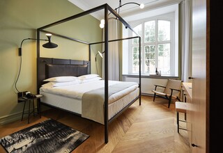 A four-poster bed with a headboard, bedside tables, a chair, and a desk.