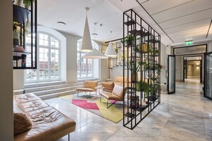 Un interior moderno con una zona de estar, un arreglo de plantas y vistas por una ventana grande.