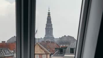 Una habitación con ventana que da a una vista de la ciudad, incluyendo una torre destacada.