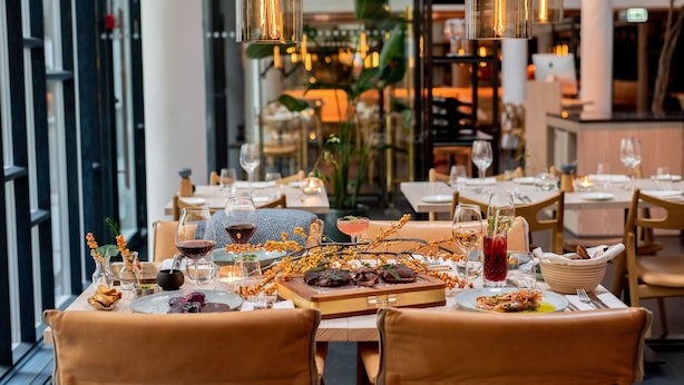 Une salle à manger de restaurant avec des tables préparées pour deux personnes, proposant une variété de plats et de boissons.