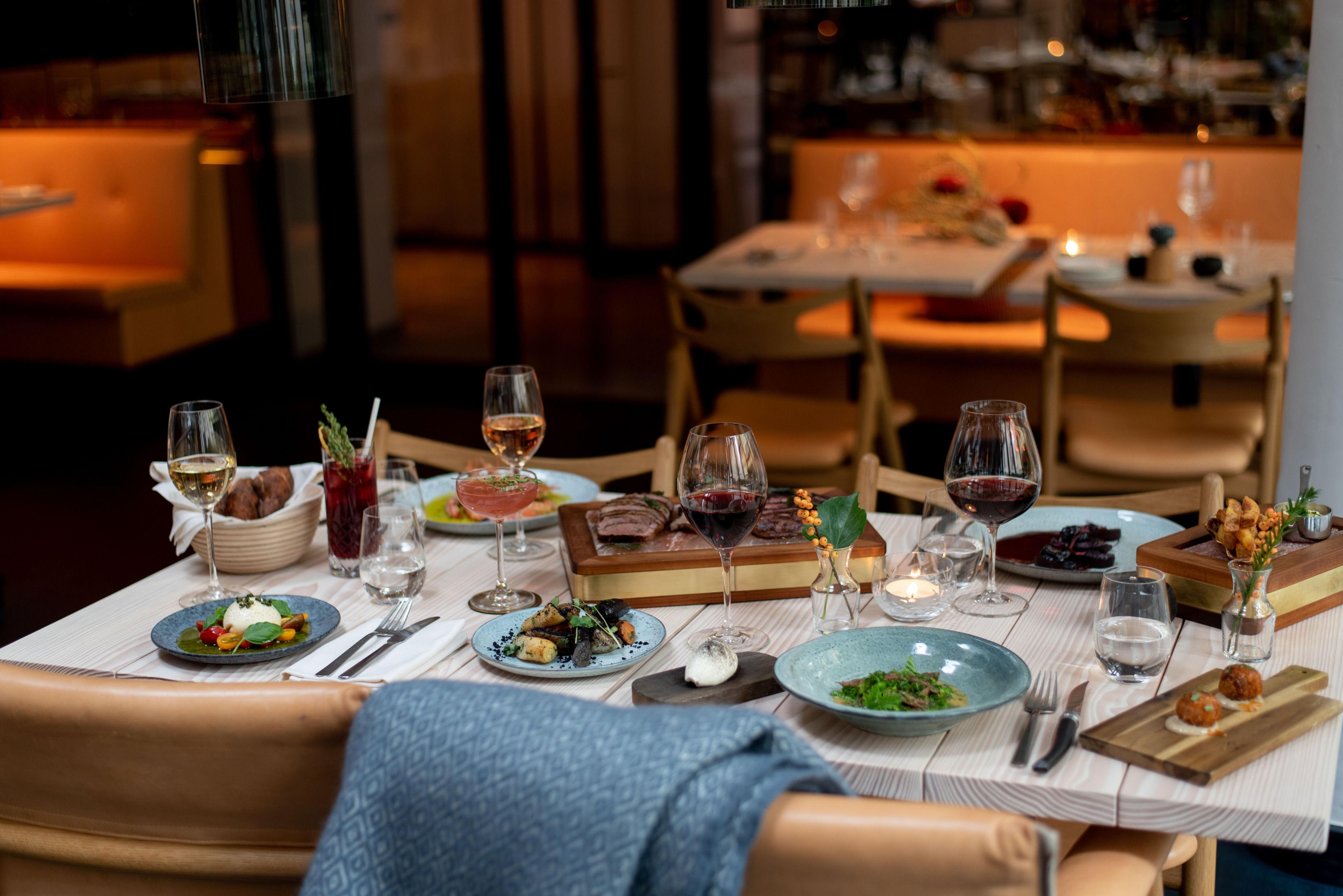 A dining table set with various dishes, glasses of wine, and candles, indicating a restaurant setting.