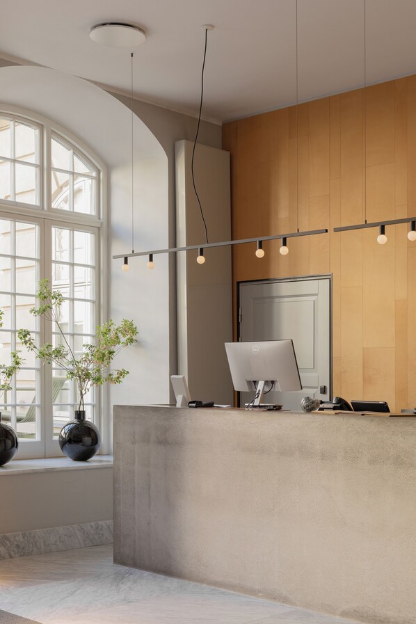 A modern reception desk with a large window, a potted plant, and a desktop computer.