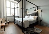 A modern bedroom with a four-poster bed, a desk, and a chair.
