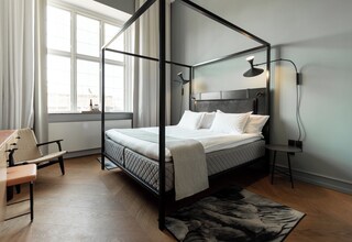 A modern bedroom with a four-poster bed, a desk, and a chair.