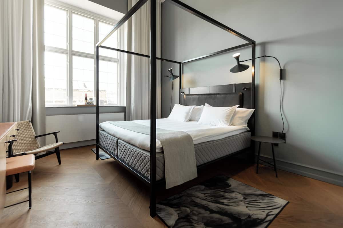 Une chambre à coucher moderne avec un lit à baldaquin, un bureau et une chaise.
