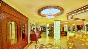 Eine Lobby mit verzierten Holztüren, einem Chandelier und einem Empfangsbereich.