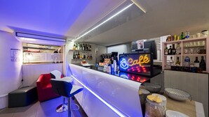 A bar area with a neon sign, shelves of liquor bottles, and bar stools. - Appart'hotel Le Pelerin (Lourdes)