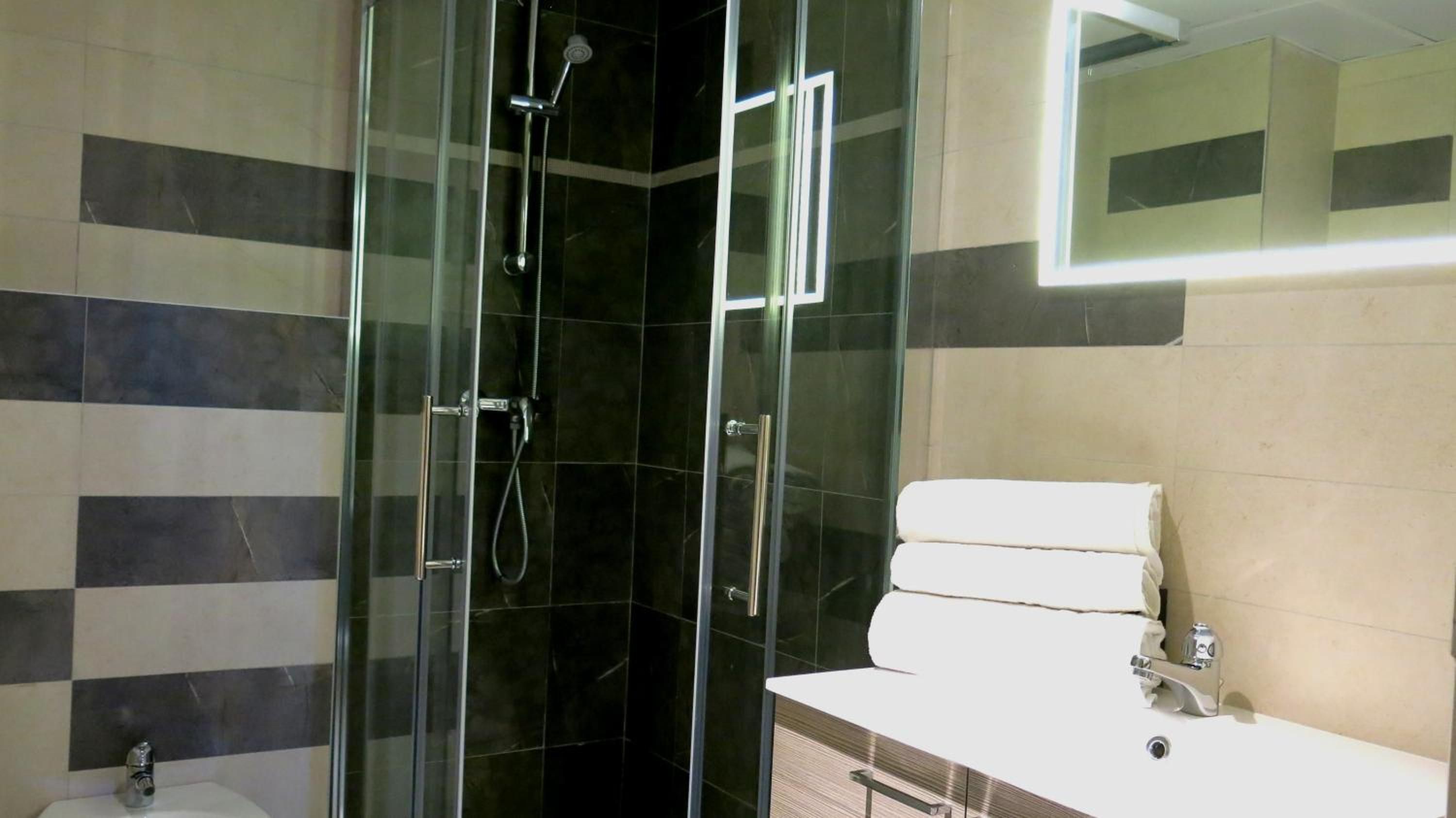 A modern bathroom with a glass-enclosed shower, a white sink, and a mirror above the sink.