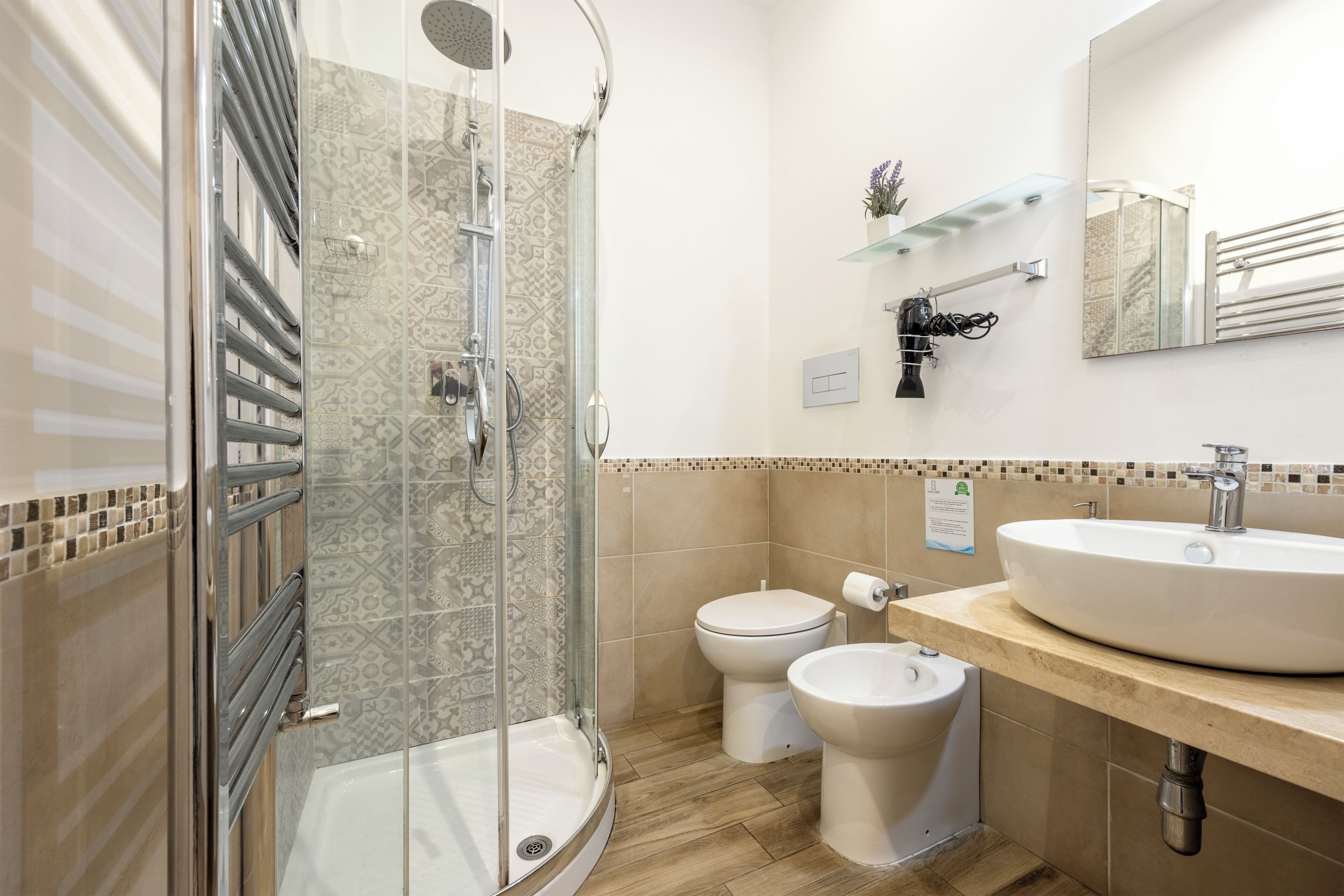 Ein modernes Badezimmer mit einer gläsernen Duschkabine, einem Waschbecken, einer Toilette und einem Bidet.