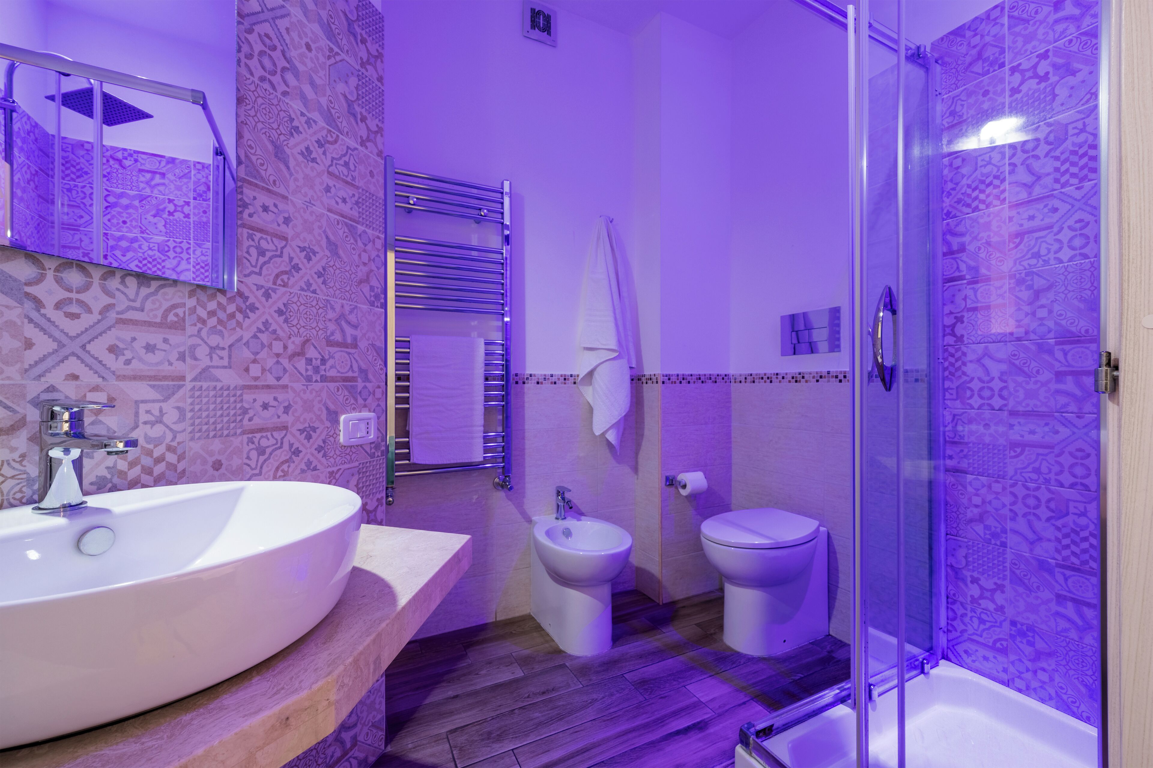 A bathroom with a large white sink, a bidet, a toilet, and a glass-enclosed shower.