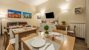 A modern dining area with wooden tables, chairs, and a television mounted on the wall. - Quinto Stabile Rooms&Suite (Palermo)