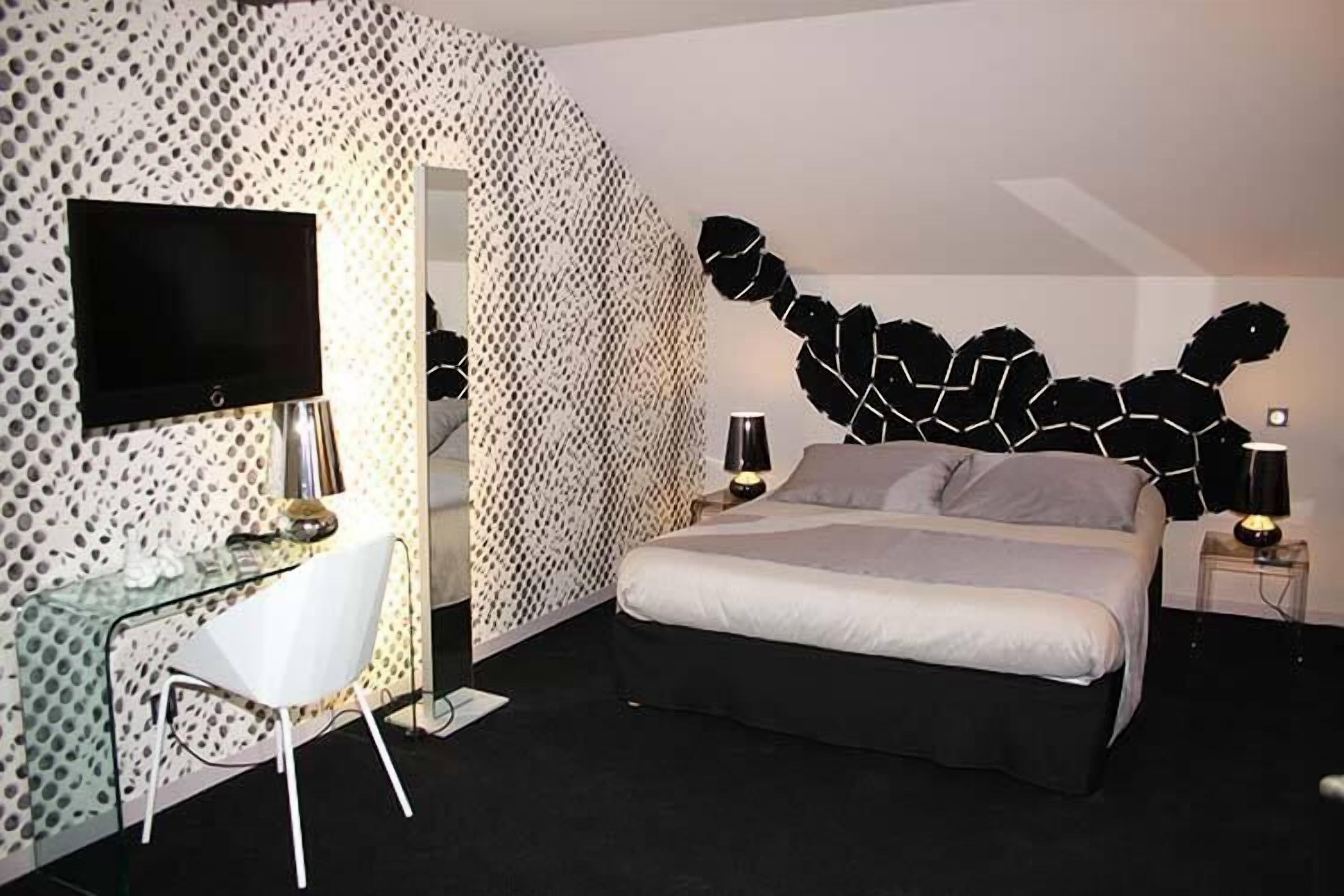 Ein modernes Schlafzimmer mit Bett, Schreibtisch und Fernseher.