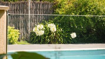 A swimming pool with a view of a garden and a wooden fence.