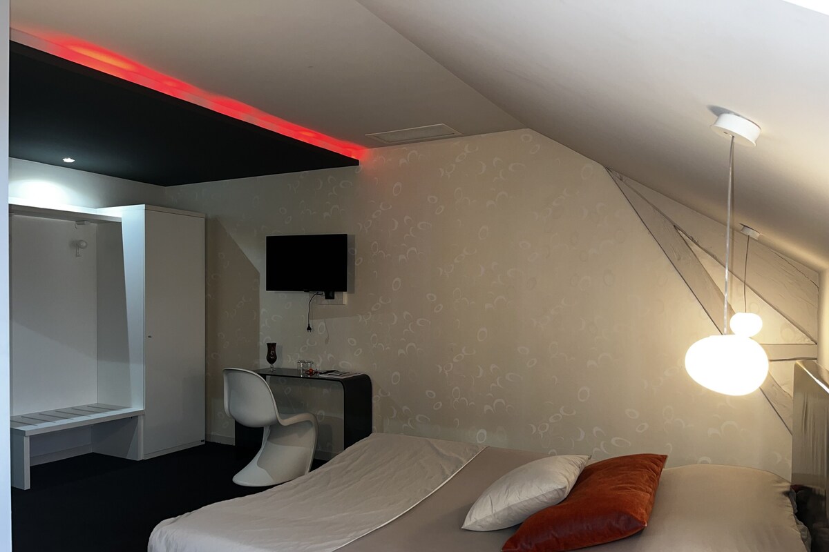 Een moderne hotelkamer met een bed, een bureau, een stoel en een televisie.