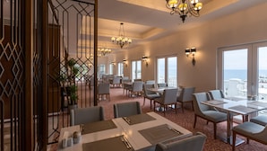 A hotel dining area with tables, chairs, and a view of the city. - Mell Hotel (Trabzon)