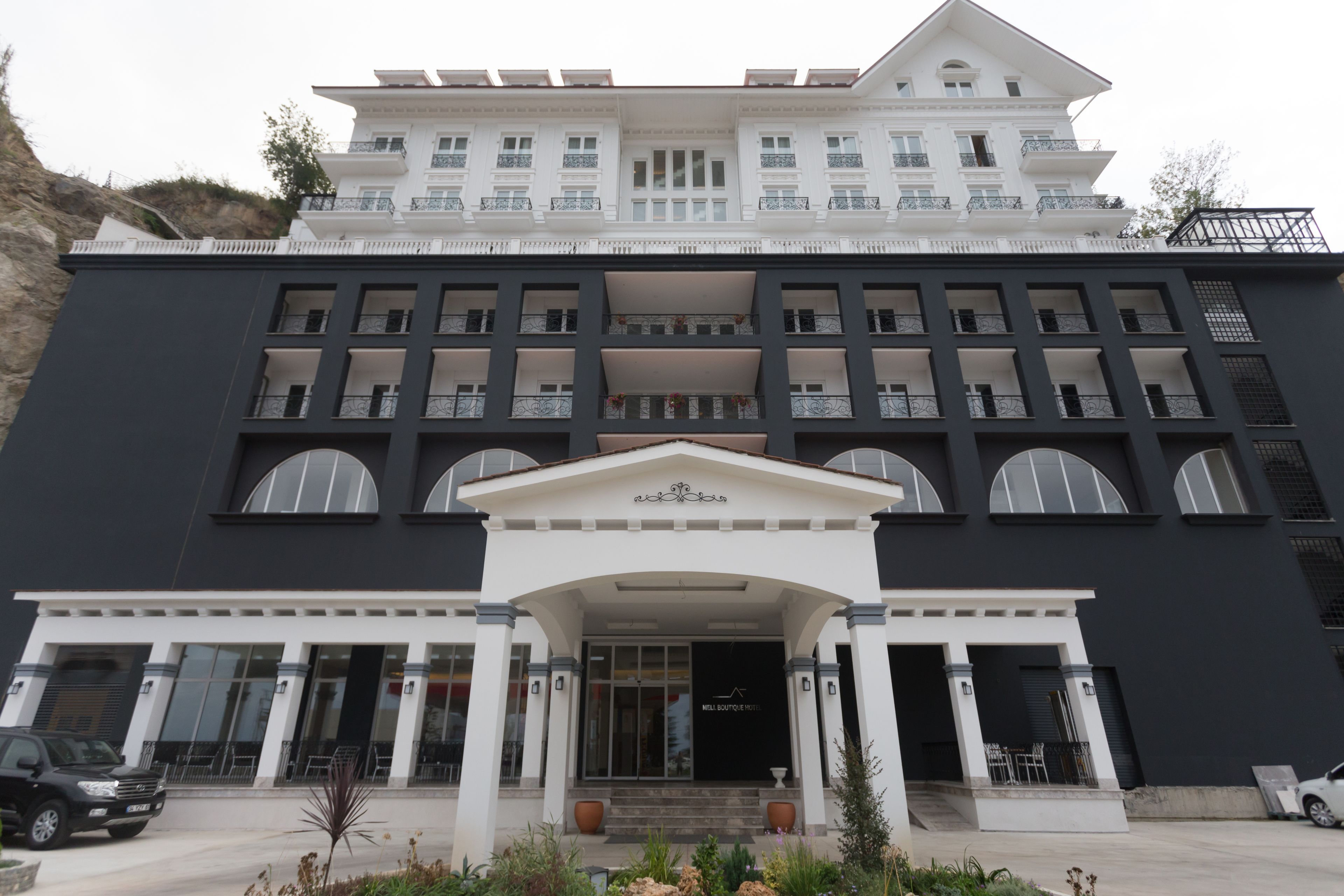Un hotel grande de varios pisos con una fachada simétrica, múltiples balcones y una entrada central con escalones.