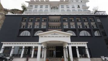 Un hotel grande de varios pisos con una fachada simétrica, múltiples balcones y una entrada central con escalones.