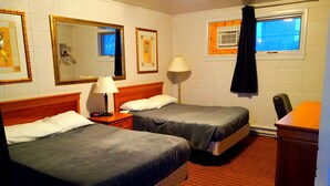 A hotel room with two beds, a nightstand with a lamp, a dresser, and a window with a curtain. - Chalet Inn Motel (Dryden)
