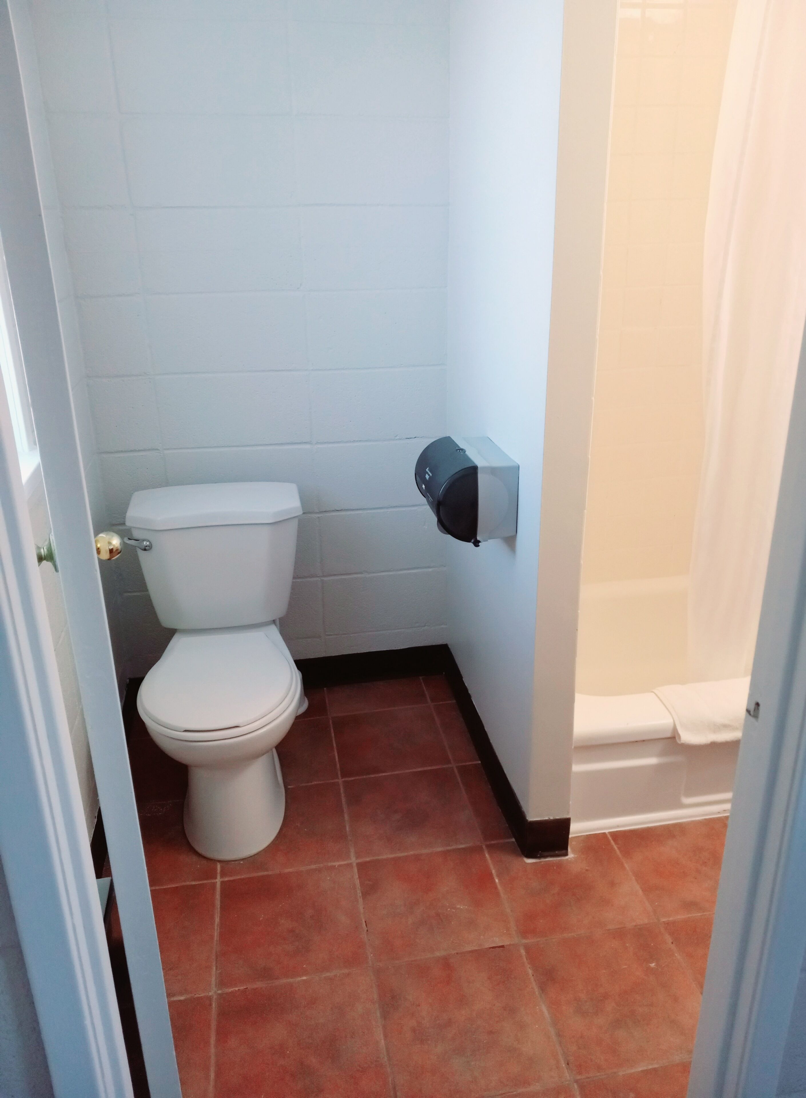 Une petite salle de bain comprenant des toilettes, un distributeur de serviettes et un espace douche.