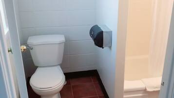 Une petite salle de bain comprenant des toilettes, un distributeur de serviettes et un espace douche.