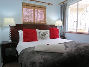 Enjoy a restful night's sleep in this inviting room with a comfortable bed, a bedside lamp, and a window offering a view of the outside.