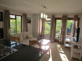 Una cocina moderna con comedor, ventanas amplias con cortinas y vistas a zonas verdes.