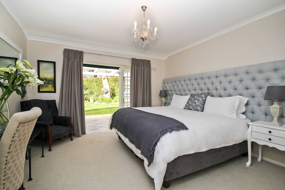 A bedroom with a large bed, a chair, a nightstand, and a chandelier.