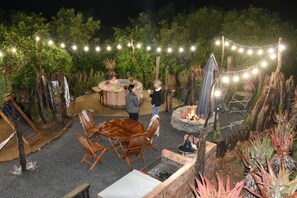 Eine Terrasse im Freien mit Whirlpool, Holzstühlen und Feuerstelle.