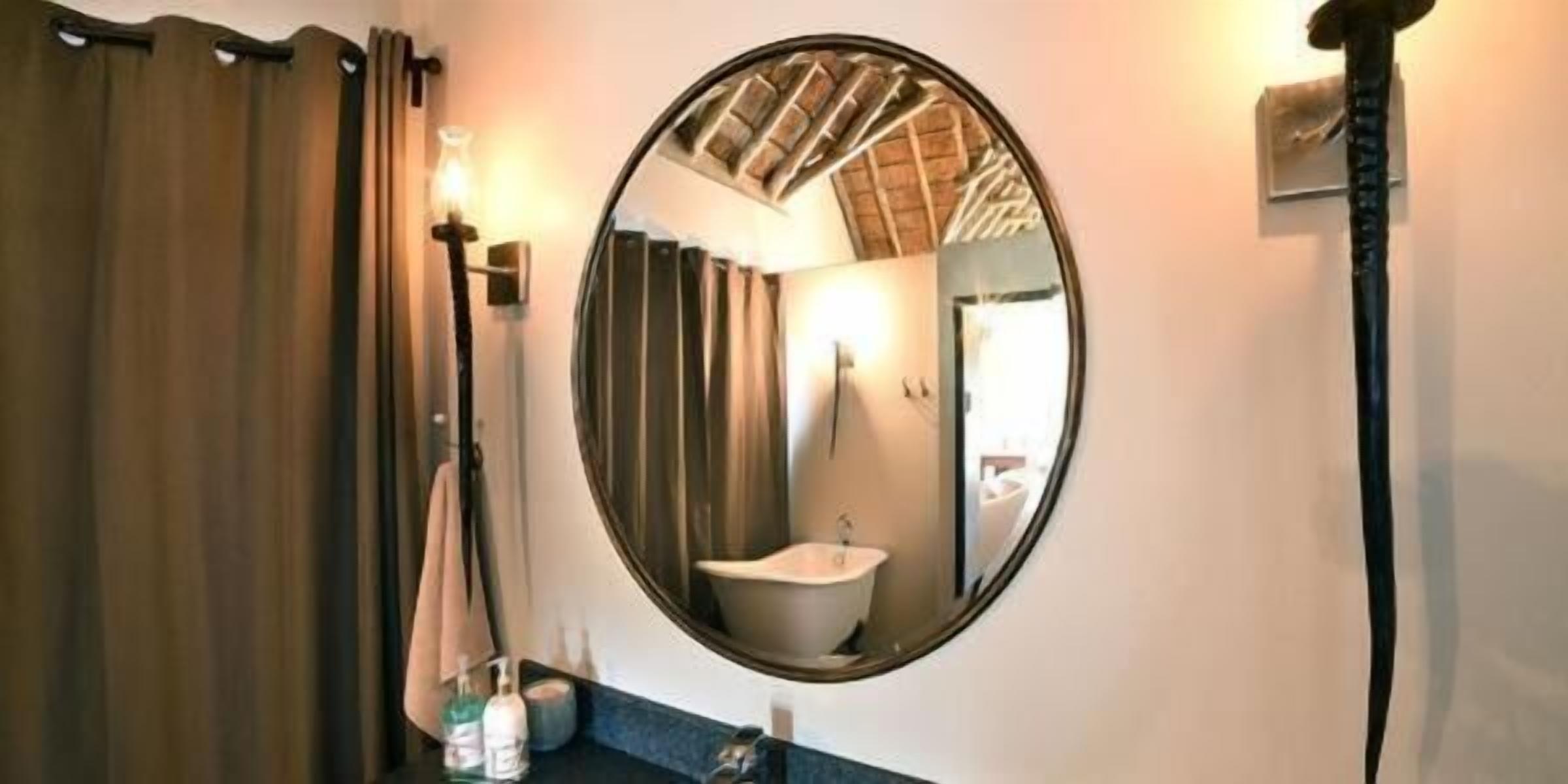 A bathroom with a round mirror, a sink, and a towel hanging on the wall.