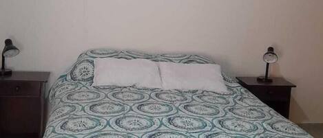 A bedroom with a bed, two bedside tables, a wall-mounted picture, and a ceiling light.