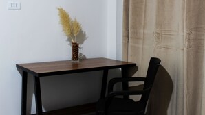 A small wooden table with a glass vase containing pampas grass, a black chair, and a beige curtain in the background. - Casa Sirius (San Pedro de Atacama)