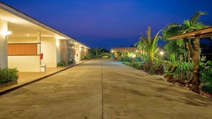 A well-lit, paved pathway leading to a building with a covered porch and outdoor seating area. - Banter Resort (Buriram)