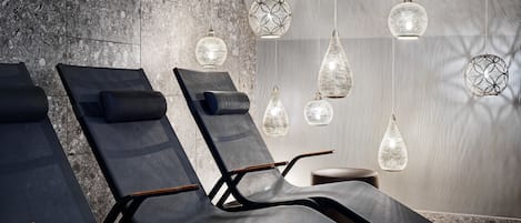 Un área de spa con sillones reclinables, pared de piedra y lámparas colgantes.