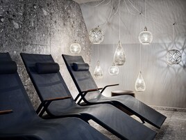 Un área de spa con sillones reclinables, pared de piedra y lámparas colgantes.