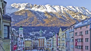 A snow-covered mountain range with a town in the foreground featuring historic buildings and a central square.