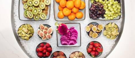 Een schaal met diverse soorten fruit en noten, gekoeld op ijs.
