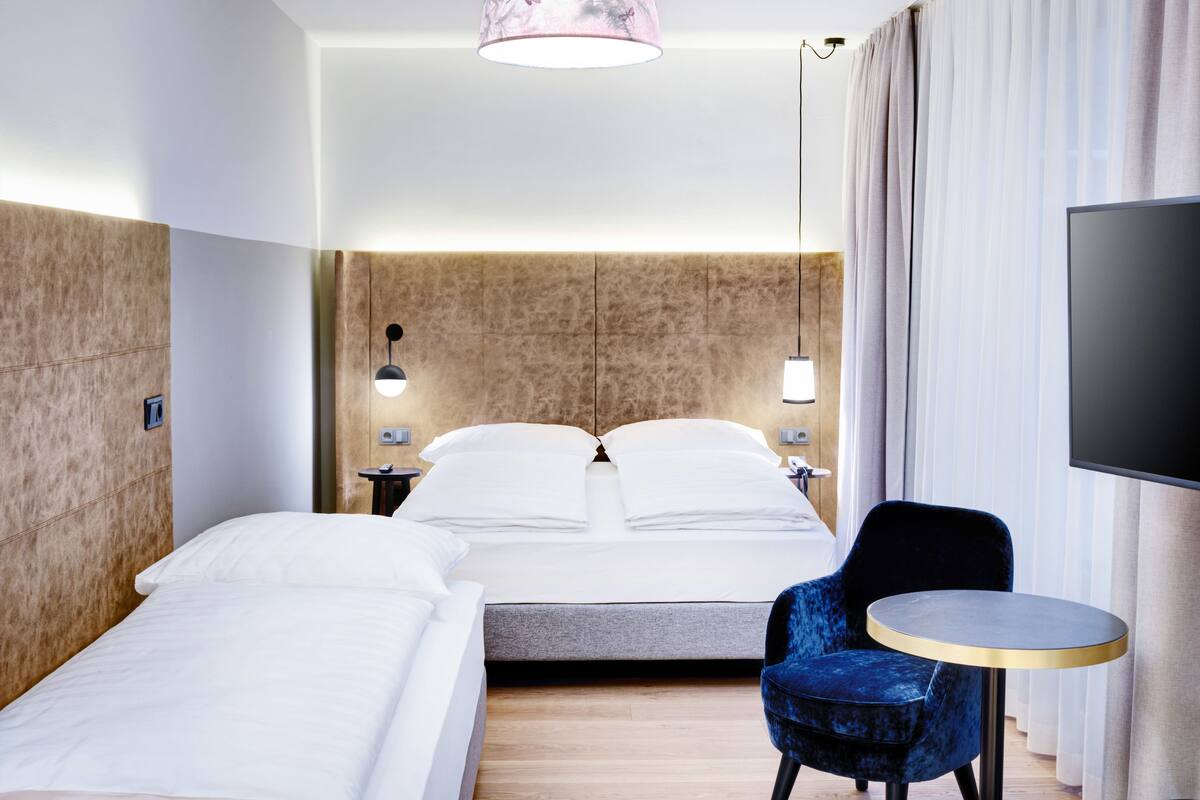 Een hotelkamer met twee bedden, een televisie, een klein rond tafeltje en een stoel.