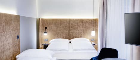 Habitación de hotel con dos camas, televisión, una mesita redonda y una silla.