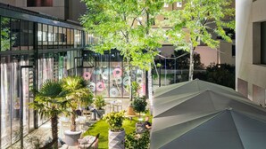 An outdoor patio area with seating, potted plants, and umbrellas.