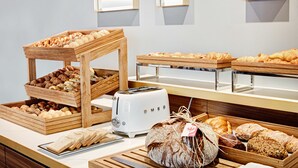 A breakfast buffet with various breads, pastries, and a toaster.