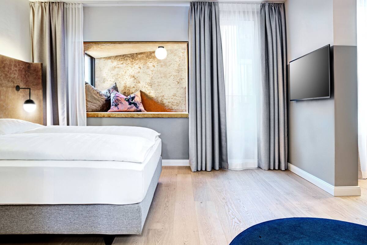 Een moderne hotelkamer met een groot bed, een flatscreen televisie, een schilderij aan de muur en een houten vloer.