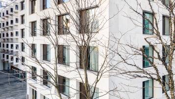 A modern multi-story building with a symmetrical facade, large windows, and a flat roof.