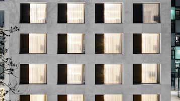 A modern hotel with a clean, geometric facade and multiple windows. The hotel has a stage area and a bar at the ground level.