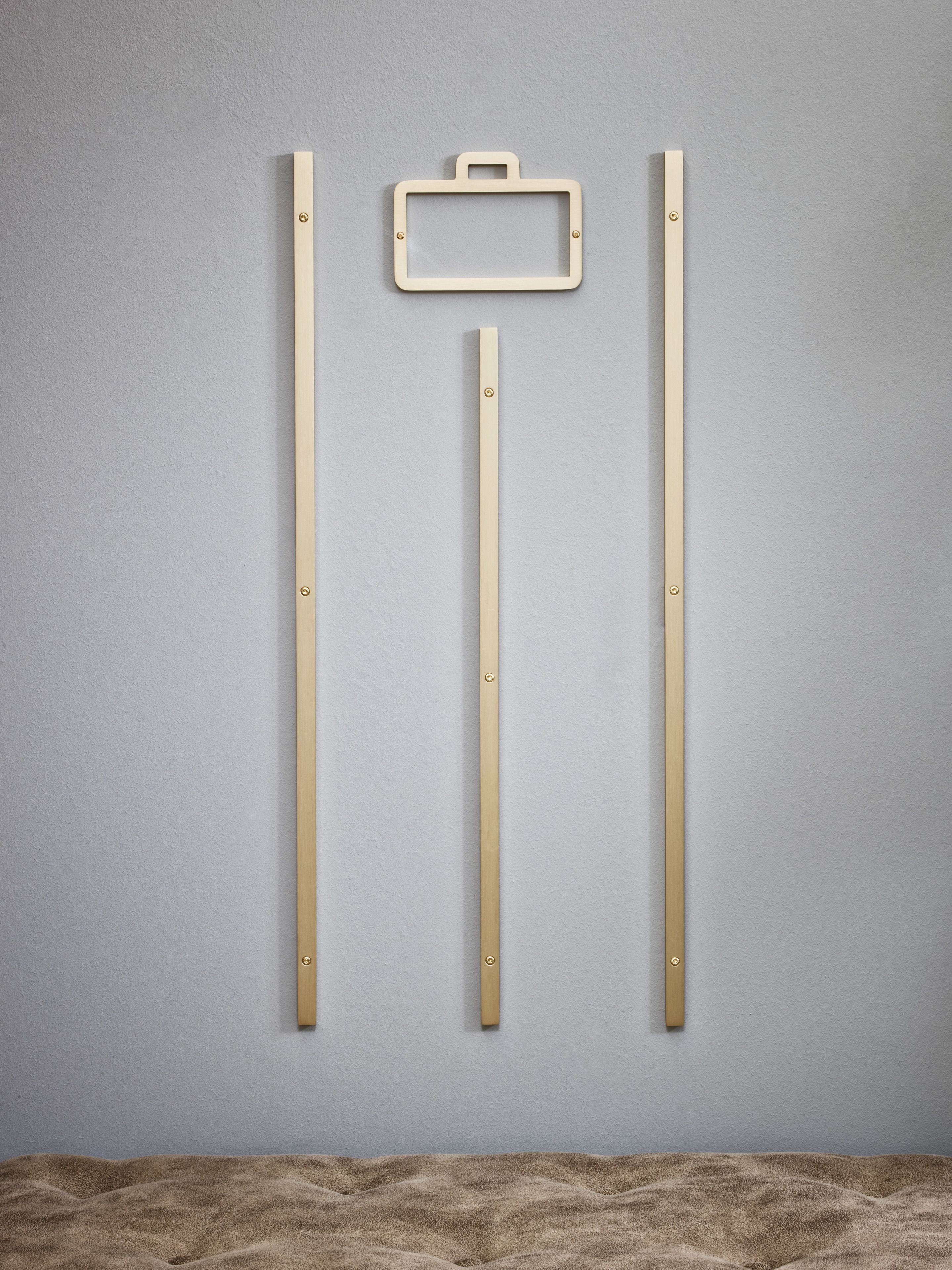 A wall-mounted wooden frame with a handle, flanked by two vertical wooden bars, against a textured wall.