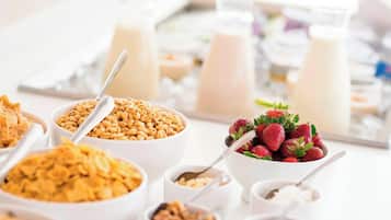 Un bufé de desayuno con diversos cereales, frutas y productos lácteos.