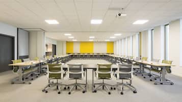 A conference room with a large oval table, multiple chairs, and a projector.
