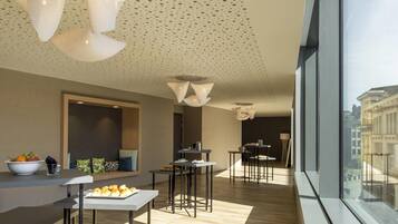 A modern interior with a dining area, a large window with a city view, and a ceiling with a perforated pattern.