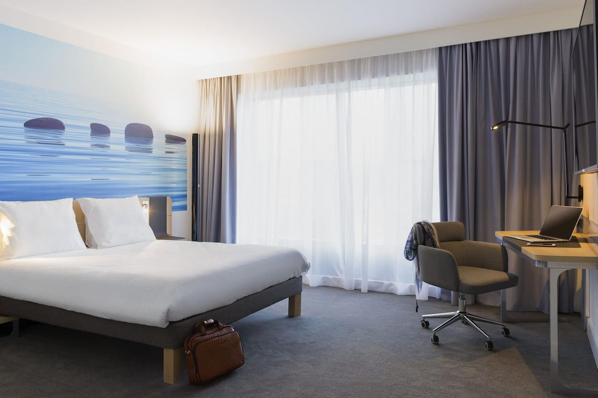 Hotellihuone, jossa on sänky, työpöytä, tuoli ja näkymä merelle.